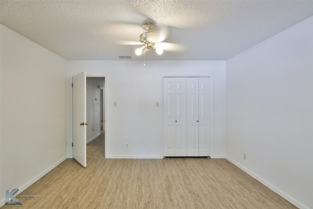 unfurnished bedroom with light hardwood / wood-style flooring, a textured ceiling, a closet, and ceiling fan