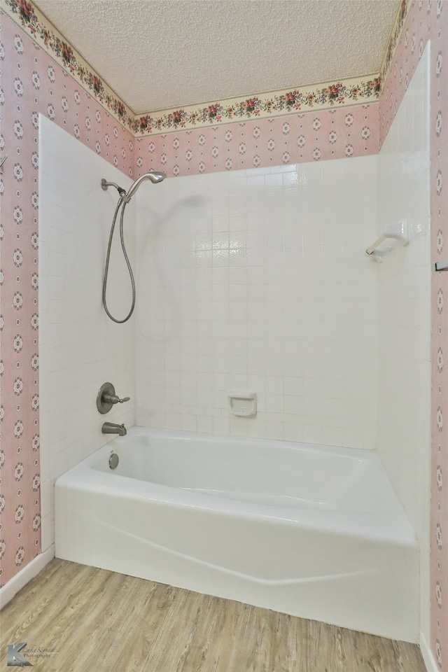 bathroom with a textured ceiling, tiled shower / bath combo, and hardwood / wood-style flooring