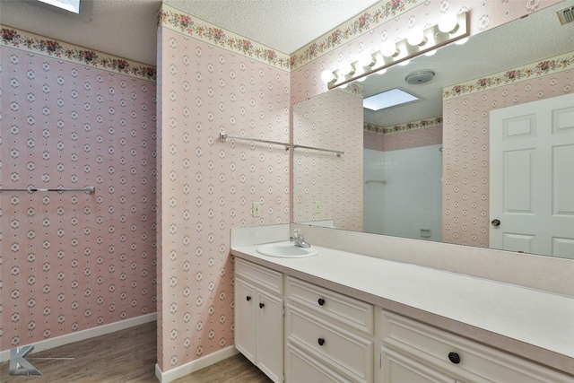 bathroom with a textured ceiling, vanity, and hardwood / wood-style flooring