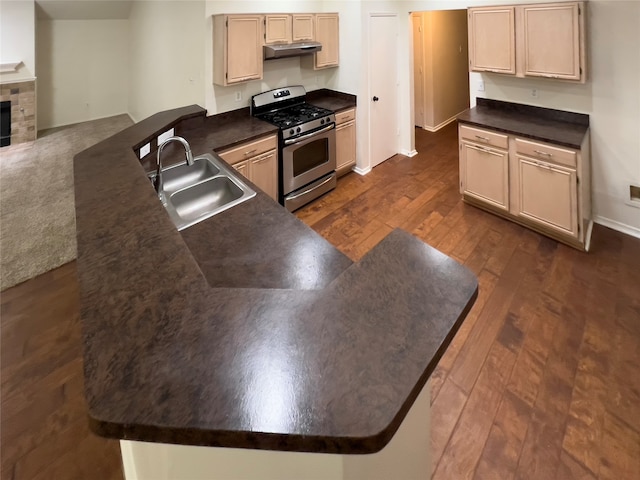 kitchen with a tile fireplace, light brown cabinets, stainless steel range with gas stovetop, sink, and dark hardwood / wood-style floors