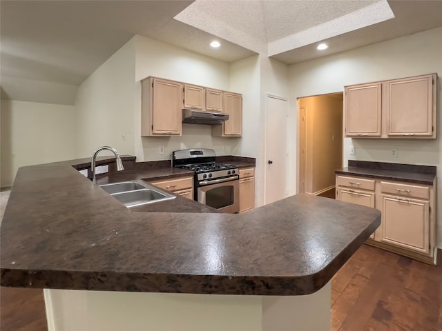 kitchen featuring dark hardwood / wood-style flooring, light brown cabinets, stainless steel gas stove, sink, and kitchen peninsula