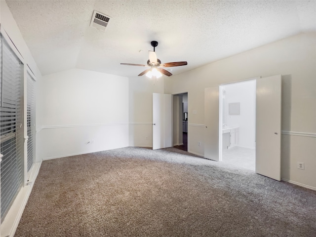 unfurnished bedroom with a textured ceiling, light carpet, vaulted ceiling, ceiling fan, and ensuite bathroom