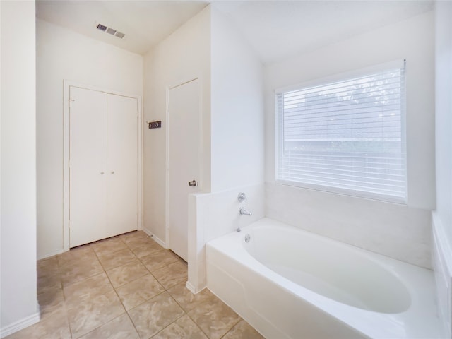 bathroom with tile patterned floors and a bath