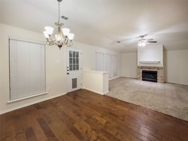 unfurnished living room featuring vaulted ceiling, ceiling fan with notable chandelier, a tile fireplace, and carpet floors