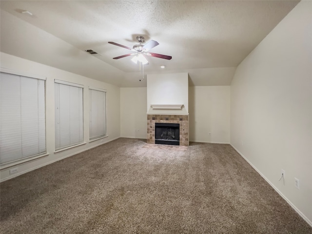 unfurnished living room featuring ceiling fan, a tiled fireplace, lofted ceiling, and carpet floors