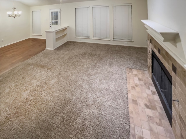 unfurnished living room featuring a tile fireplace, a notable chandelier, and light hardwood / wood-style floors