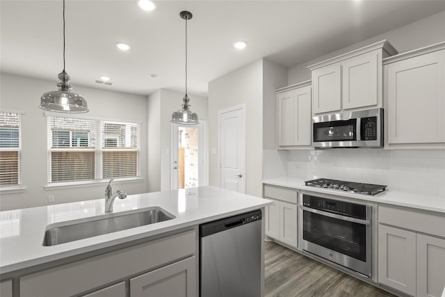 kitchen featuring sink, hanging light fixtures, gray cabinets, stainless steel appliances, and decorative backsplash