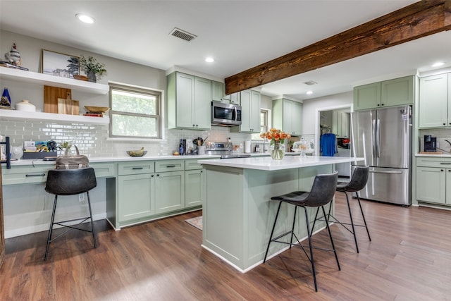 kitchen featuring beamed ceiling, stainless steel appliances, dark wood-type flooring, and a kitchen bar