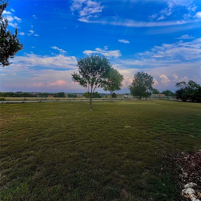 yard at dusk featuring a rural view