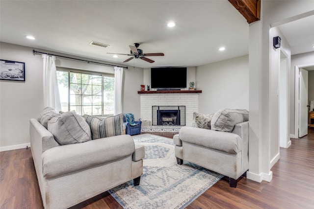 living room with ceiling fan, a fireplace, and dark hardwood / wood-style flooring