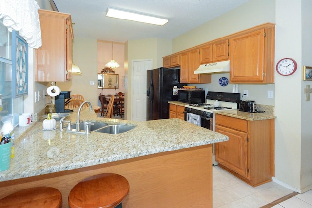 kitchen featuring sink, a kitchen breakfast bar, light stone counters, kitchen peninsula, and black appliances