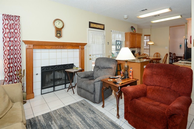 living room featuring a tile fireplace, a textured ceiling, and light tile patterned flooring