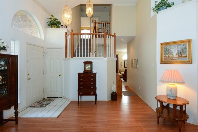 entrance foyer with a towering ceiling, ornamental molding, and hardwood / wood-style flooring