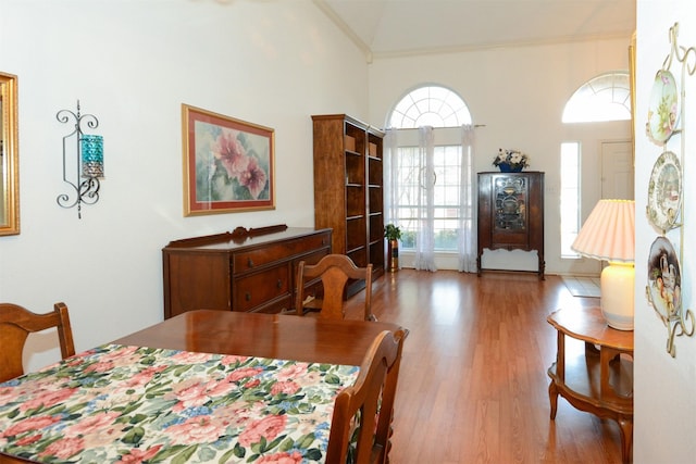 dining area with wood-type flooring, lofted ceiling, and ornamental molding