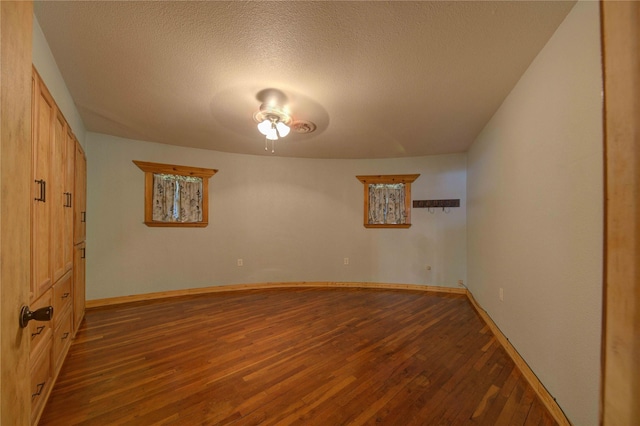 unfurnished room featuring a textured ceiling and dark hardwood / wood-style flooring