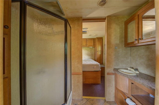 bathroom with tile patterned floors, vanity, and a shower with door