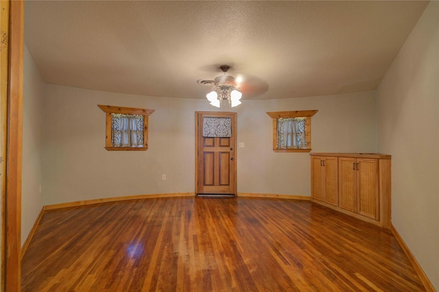 empty room with ceiling fan, dark hardwood / wood-style floors, and a textured ceiling