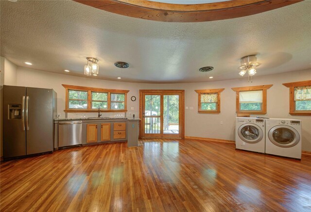 laundry area with light hardwood / wood-style flooring, sink, washer and clothes dryer, and a textured ceiling