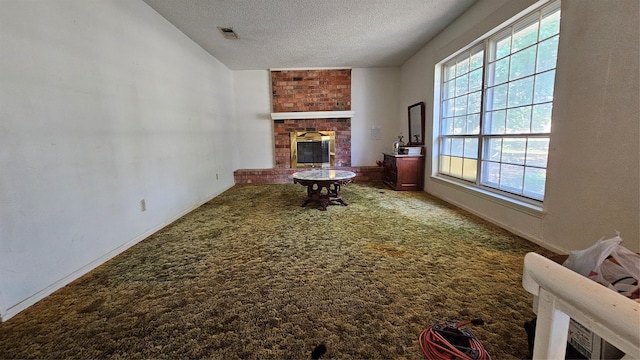 sitting room with carpet floors, brick wall, a textured ceiling, and a brick fireplace