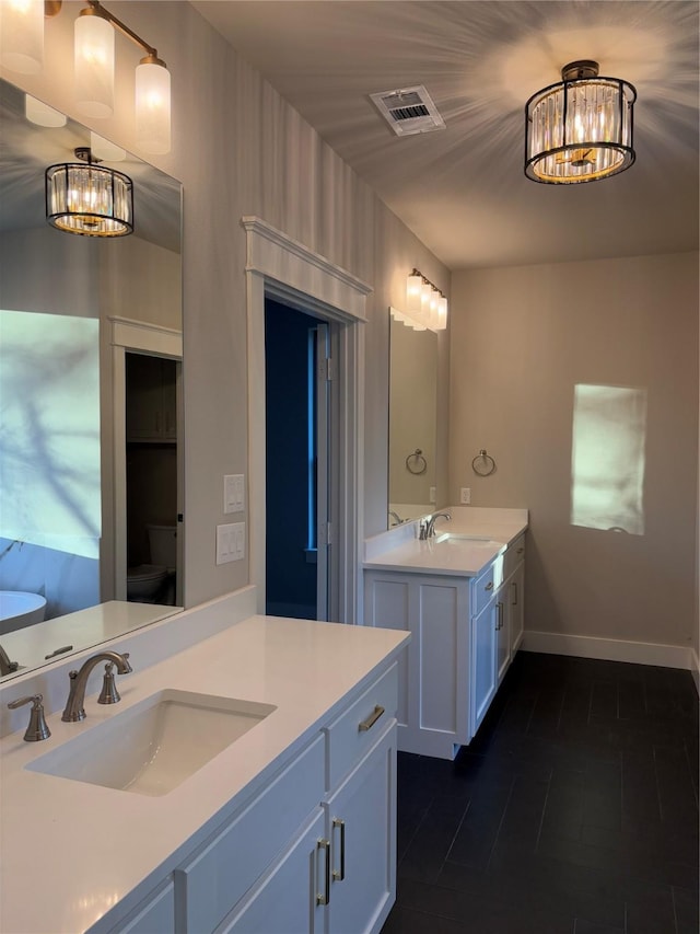 bathroom with toilet, a chandelier, and vanity