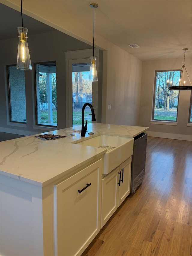 kitchen featuring a notable chandelier, light stone countertops, white cabinetry, and decorative light fixtures