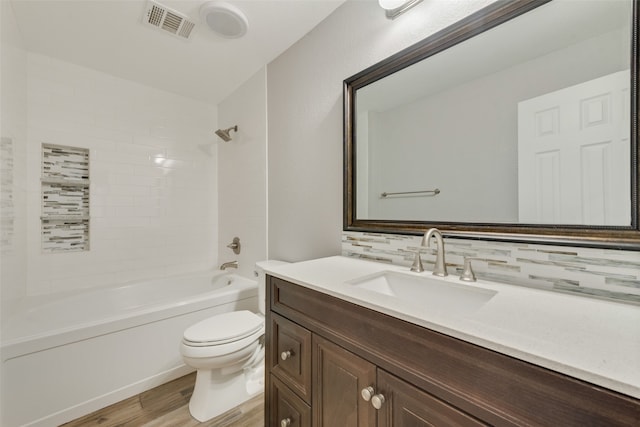 full bathroom with tiled shower / bath, tasteful backsplash, wood-type flooring, toilet, and vanity