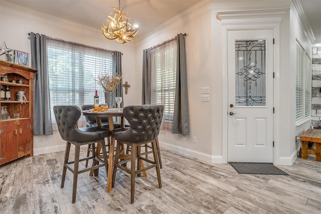 dining area with light wood-type flooring, ornamental molding, and an inviting chandelier