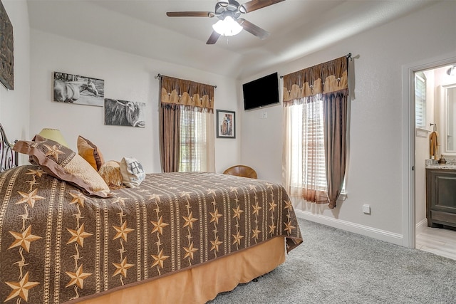 carpeted bedroom featuring ensuite bath, multiple windows, vaulted ceiling, and ceiling fan