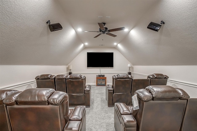 carpeted home theater featuring ceiling fan and vaulted ceiling