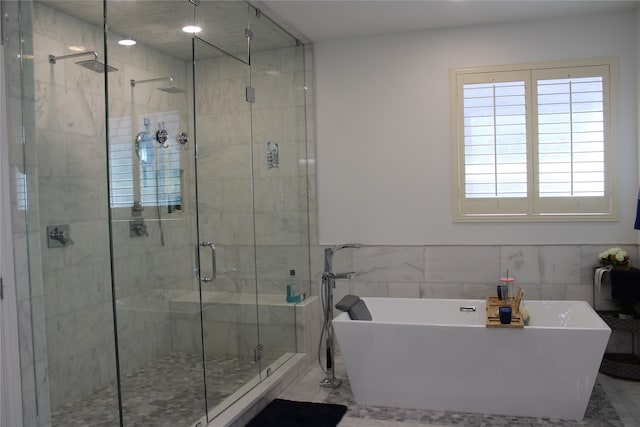 bathroom featuring shower with separate bathtub, tile walls, and tile patterned flooring