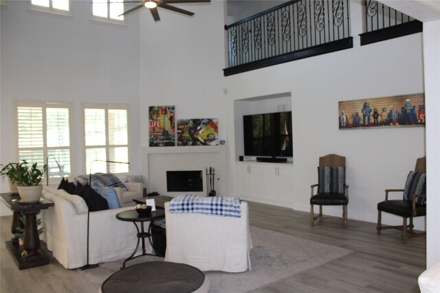 living room with ceiling fan, hardwood / wood-style flooring, and a high ceiling