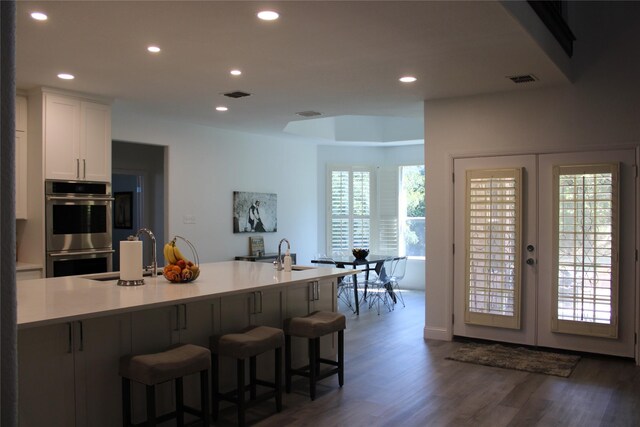 kitchen featuring sink, dark hardwood / wood-style flooring, a kitchen bar, and double oven