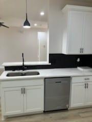 kitchen with hanging light fixtures, sink, white cabinetry, dishwasher, and light hardwood / wood-style floors