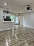 unfurnished living room featuring wood-type flooring and ceiling fan