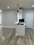 kitchen with decorative light fixtures, white cabinets, and light hardwood / wood-style flooring