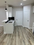 kitchen with pendant lighting, kitchen peninsula, white cabinets, and light hardwood / wood-style flooring