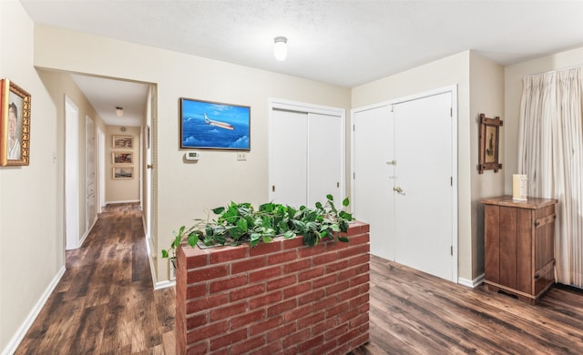 hall with a textured ceiling and dark hardwood / wood-style flooring