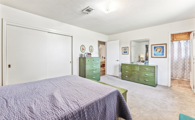 carpeted bedroom featuring a textured ceiling, a closet, and ensuite bathroom