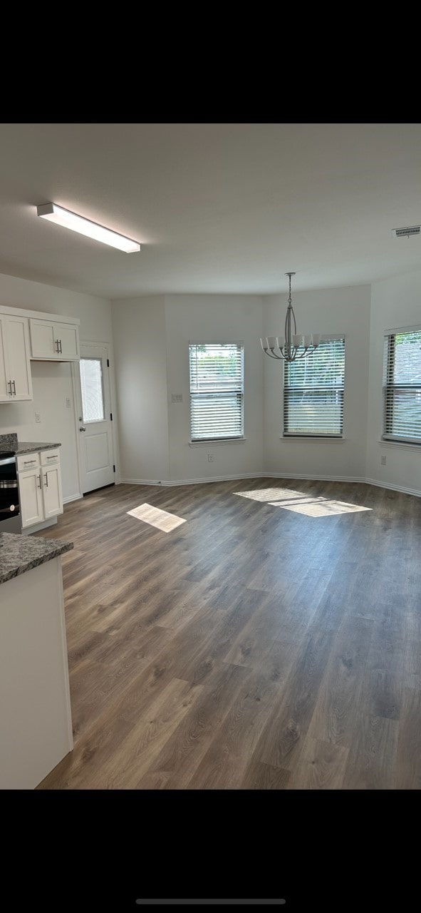 unfurnished dining area featuring a notable chandelier and dark hardwood / wood-style flooring