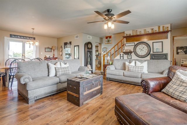 living room featuring light wood-type flooring and ceiling fan with notable chandelier