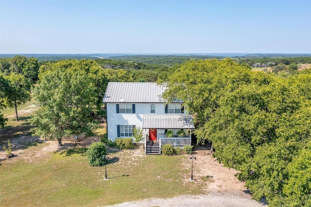 view of front of property with a forest view, a front lawn, metal roof, and covered porch