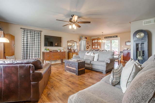 8716 County Road 1224a, Rio Vista, TX 76093 - living area with visible vents, light wood-style flooring, and ceiling fan with notable chandelier