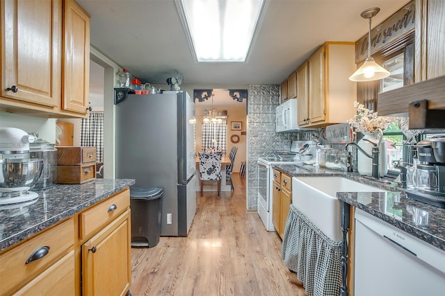 kitchen with decorative backsplash, light hardwood / wood-style flooring, hanging light fixtures, dark stone countertops, and white appliances