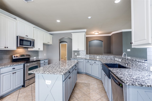 kitchen featuring a center island, appliances with stainless steel finishes, crown molding, and white cabinets