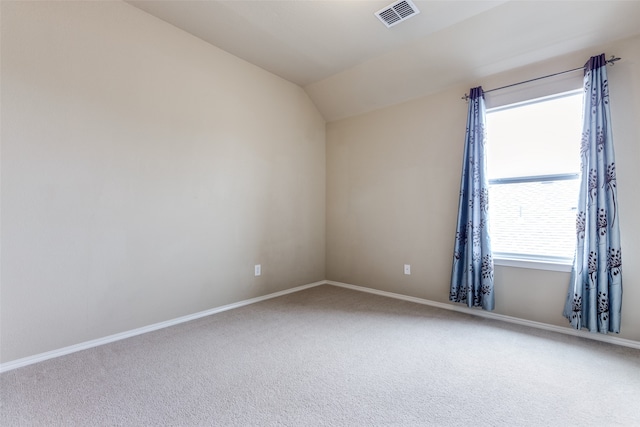 carpeted spare room featuring a healthy amount of sunlight and vaulted ceiling