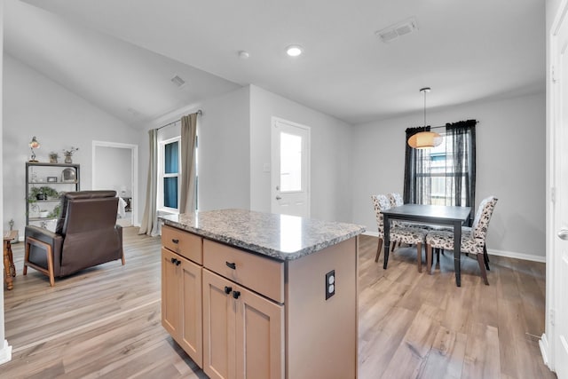 kitchen featuring vaulted ceiling, a center island, light wood-type flooring, light brown cabinets, and hanging light fixtures