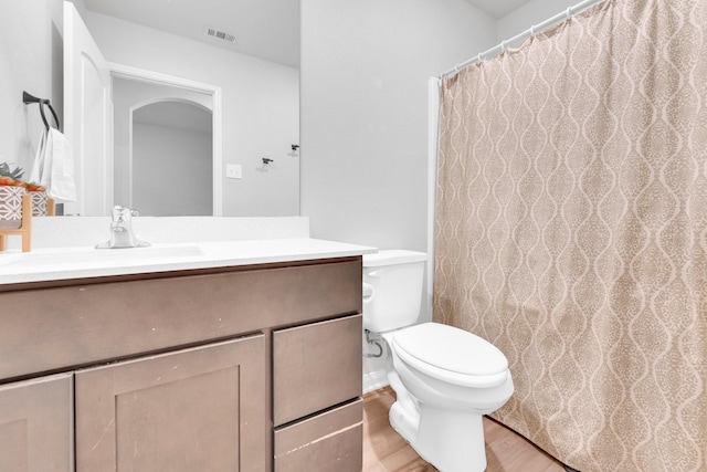 bathroom with toilet, vanity, and wood-type flooring