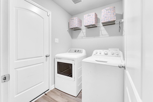 laundry room with separate washer and dryer and light hardwood / wood-style flooring