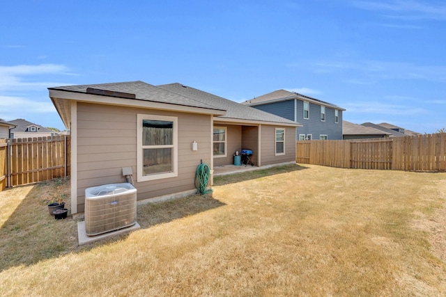 rear view of property featuring central AC and a yard