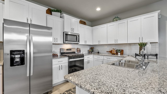 kitchen featuring appliances with stainless steel finishes, backsplash, sink, and white cabinetry